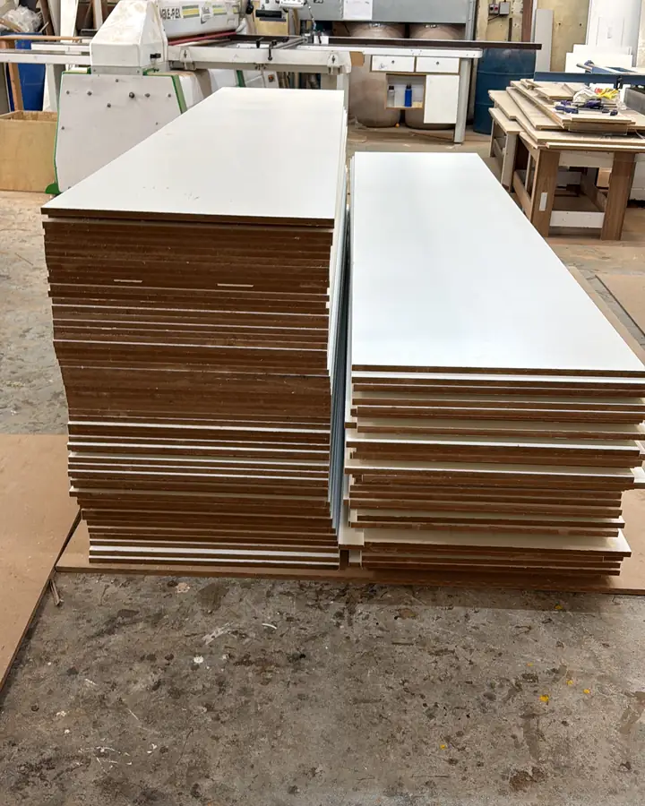 Pilhas de peças de MDF cortadas ao lado da seccionadora